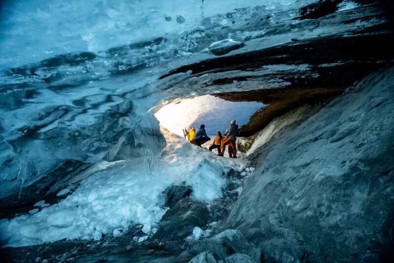Wandelaars in een blauwe ijsgrot tijdens een gletsjerwandeling op de Nigardsbreen.