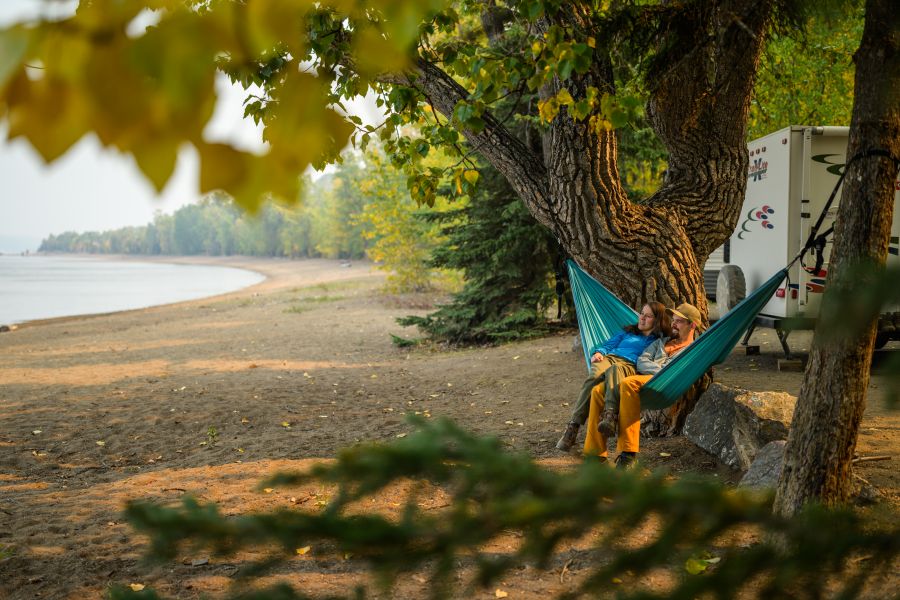 A couple relaxes in their hammock at an RV site on Stuart Lake in Paarens Beach Park.