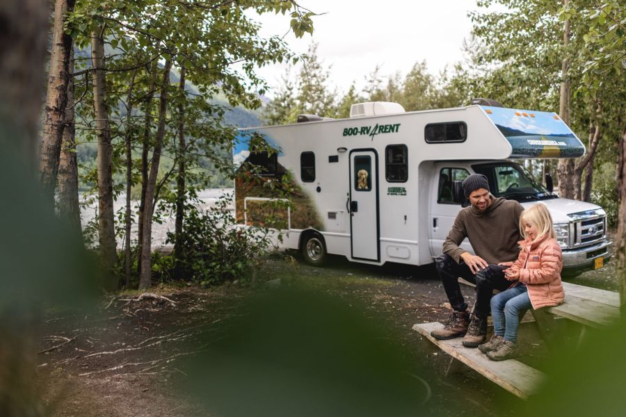 Mensen op een picknick bankje naast een camper van Cruise Canada.