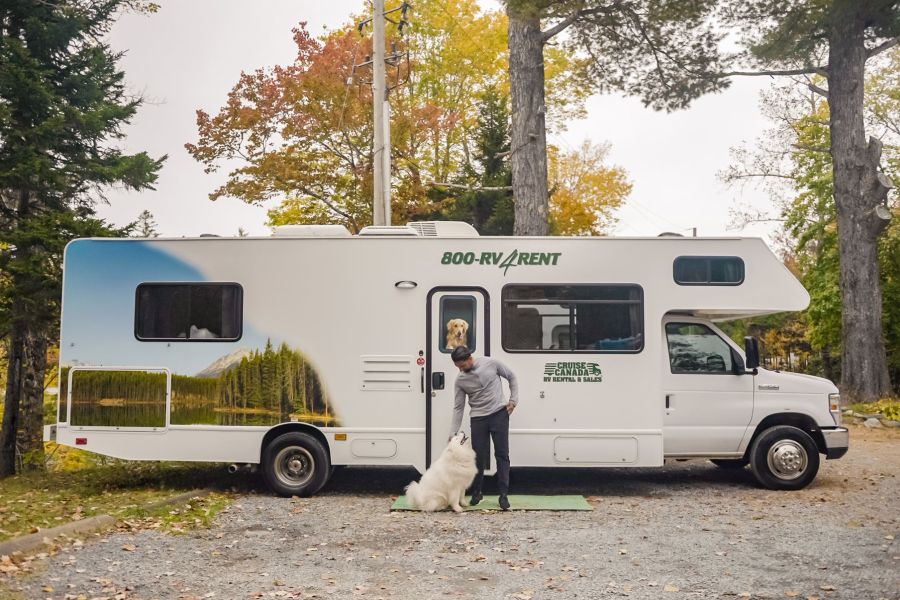Man met hond voor een camper van Cruise Canada.