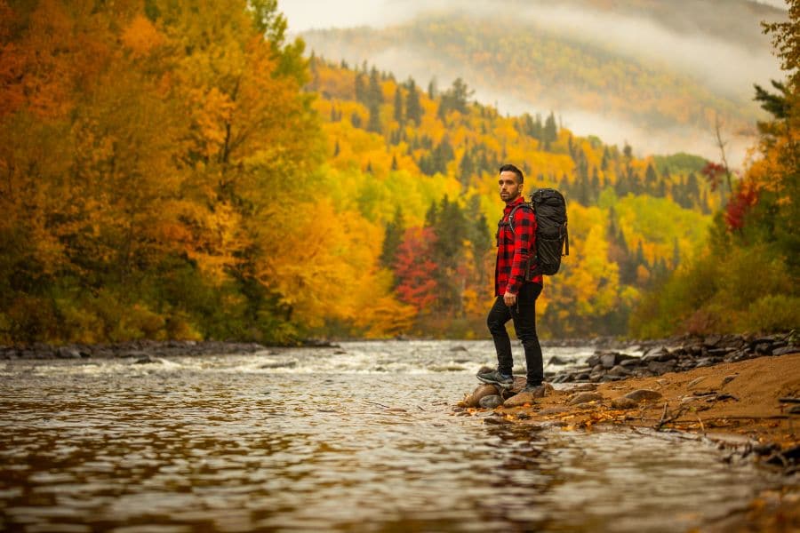 Man staat aan het water in de herfst in Parc National de la Jacques-Cartier in Canada