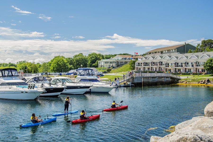 Mensen in kano’s en op een paddleboard op het water voor Oak Island Resort in Nova Scotia in Canada.