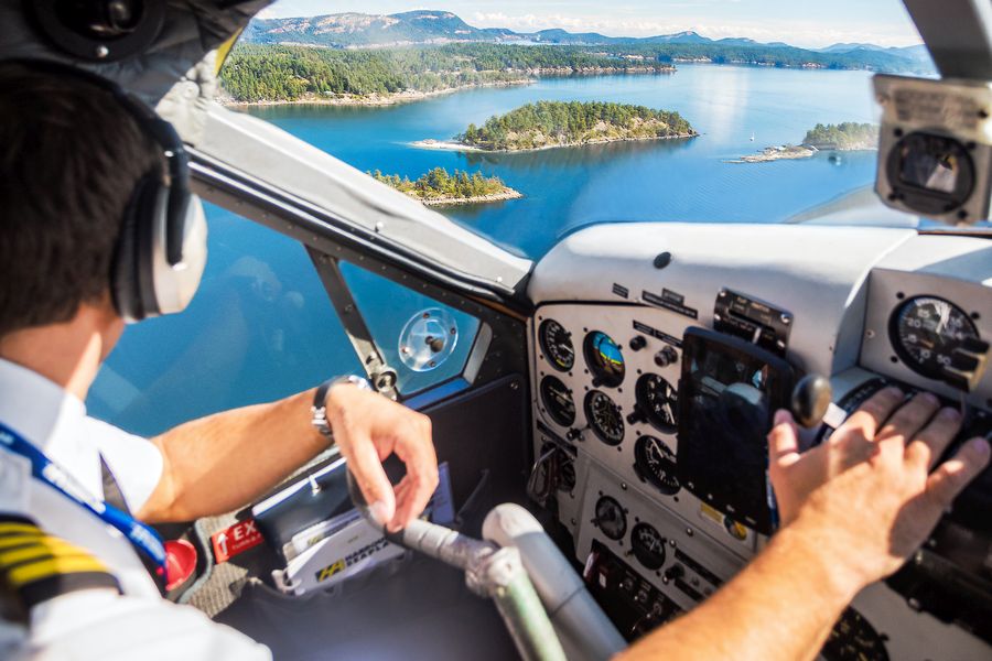 Piloot in de cockpit van een watervliegtuig boven de wateren van British Columbia.