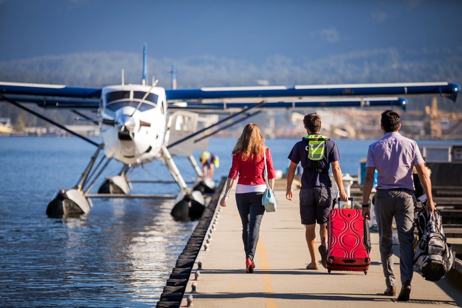 Passagiers op een steiger in de haven van Vancouver met een watervliegtuig op de achtergrond.