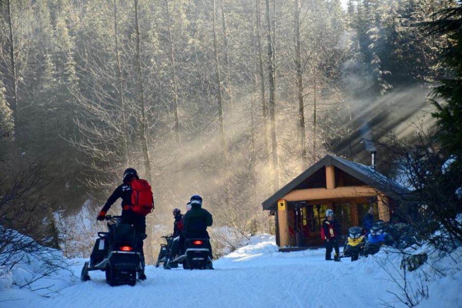 Sneeuwscooters met huisje op de achtergrond in Whistler in West-Canada.