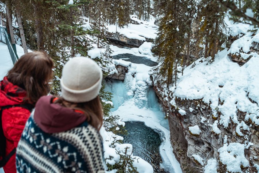 Wandelaars kijken uit over Johnston Canyon tijdens een ijswandel excursie in Banff Canada