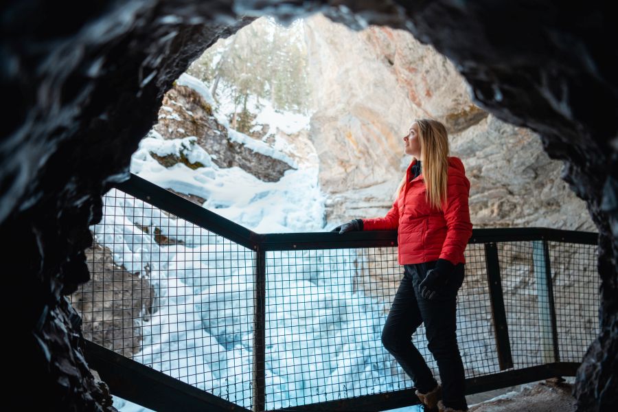 Vrouw in een grot in Johnston Canyon tijdens een ijswandel excursie in Banff Canada