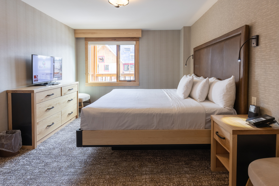 Slaapkamer met 1 king in een superior suite met aparte slaapkamer bij Moose Hotel & Suites in Banff tijdens een wintersportreis naar Canada