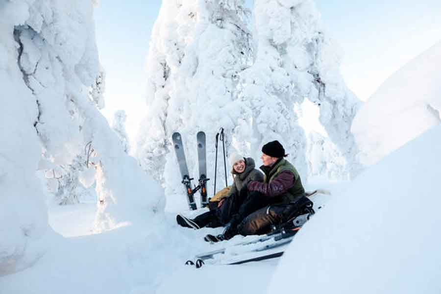 Echtpaar in de sneeuw met forest skis in Levi