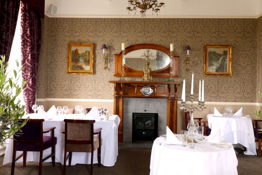 Het restaurant van het Causeway Hotel in Bushmills met gedekte tafels die vlakbij een openhaard staan