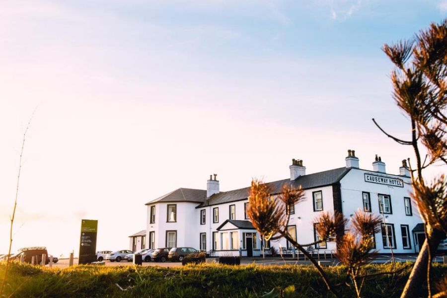 De gevel van het Causeway Hotel in Bushmills met een gekleurde lucht