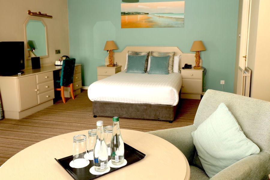 Een tweepersoonskamer met een opgemaakt bed waar een zithoek in zit in het Causeway Hotel in Bushmills