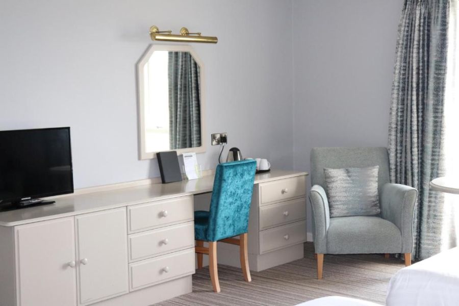 Een bureau in een kamer van het Causeway Hotel in Bushmills met een blauwe stoel