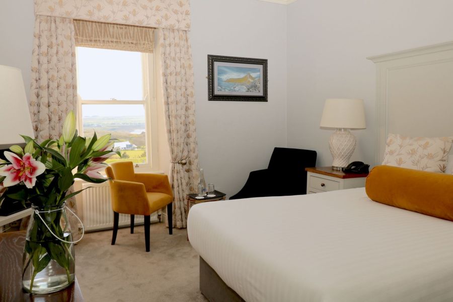 Een tweepersoonskamer in het Causeway Hotel in Bushmills met een wit opgemaakt bed