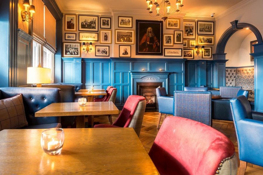 Het bargedeelte in het Bishop`s Gate Hotel in Derry met gekleurde stoelen en schilderijen aan de muur