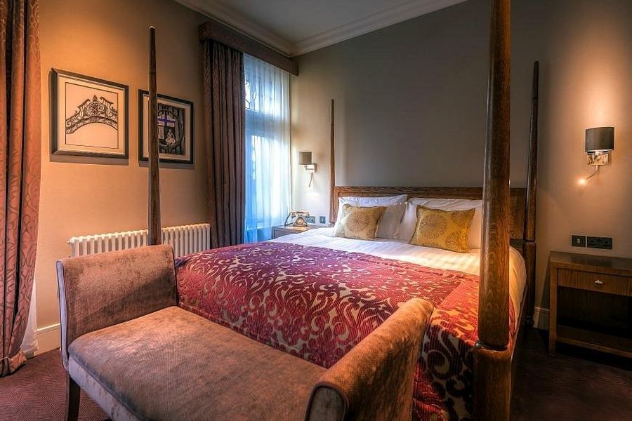Een tweepersoonskamer in het Bishop`s Gate Hotel in Derry met een wit opgemaakt bed en een rode plaid