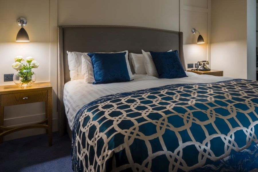 Een tweepersoonskamer met een wit opgemaakt bed en een plaid met print in het Bishop`s Gate Hotel in Derry