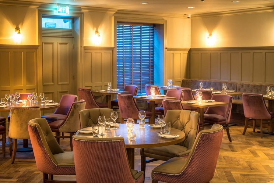 Het restaurant van het Bishop`s Gate Hotel in Derry met gedekte tafels en paarse stoelen