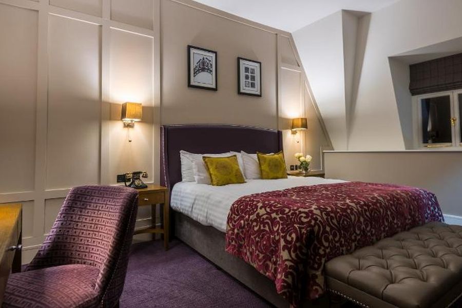 Een tweepersoonskamer in het Bishop`s Gate Hotel in Derry met een wit opgemaakt bed met een rode plaid