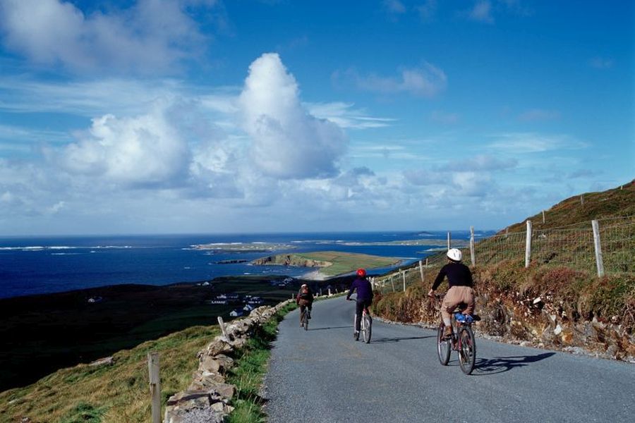 Drie fietsers dalen af in bij de kust van Dingle