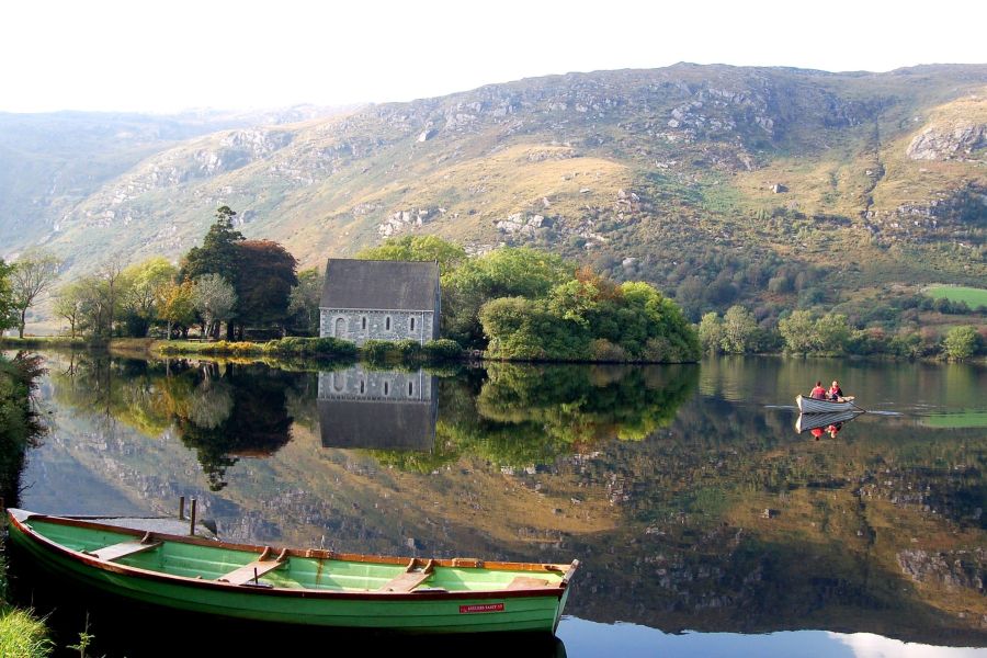 Uitzicht op de bergen in West Cork met een bootje in het meer waar twee mensen in roeien