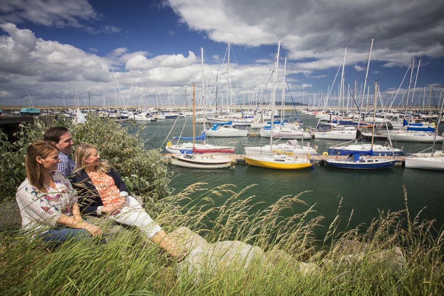 Gekleurde bootjes in de haven waar drie mensen naar kijken