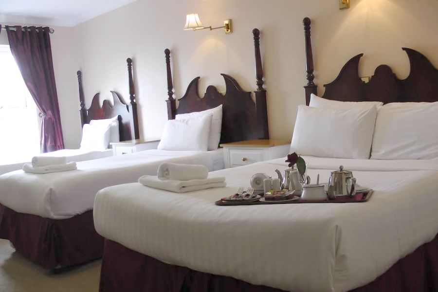 Een vierpersoonskamer van het hotel met opgemaakte bedden met wit beddengoed