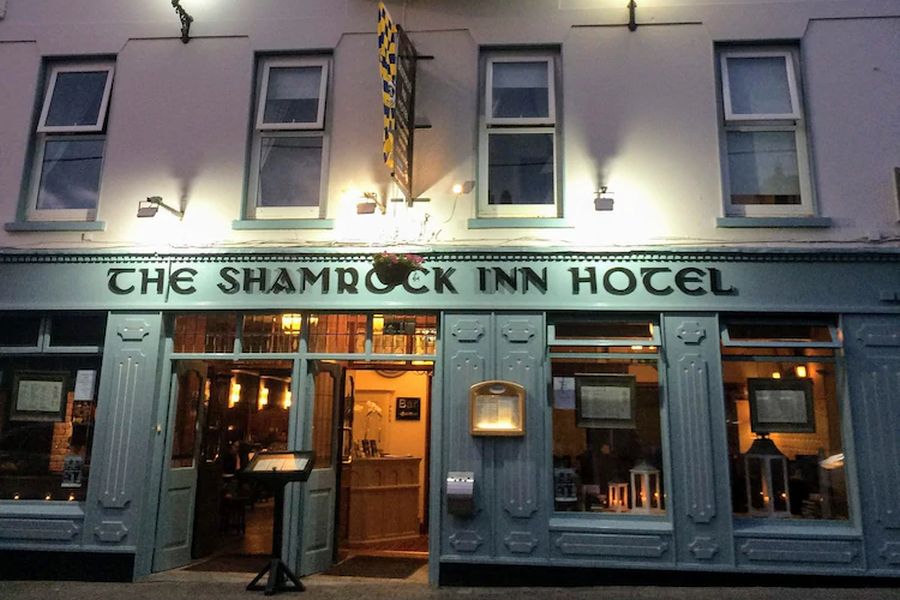 De voorkant van het Shamrock Inn Hotel waarbij de lampen aan staan en het licht schijnt op het gebouw