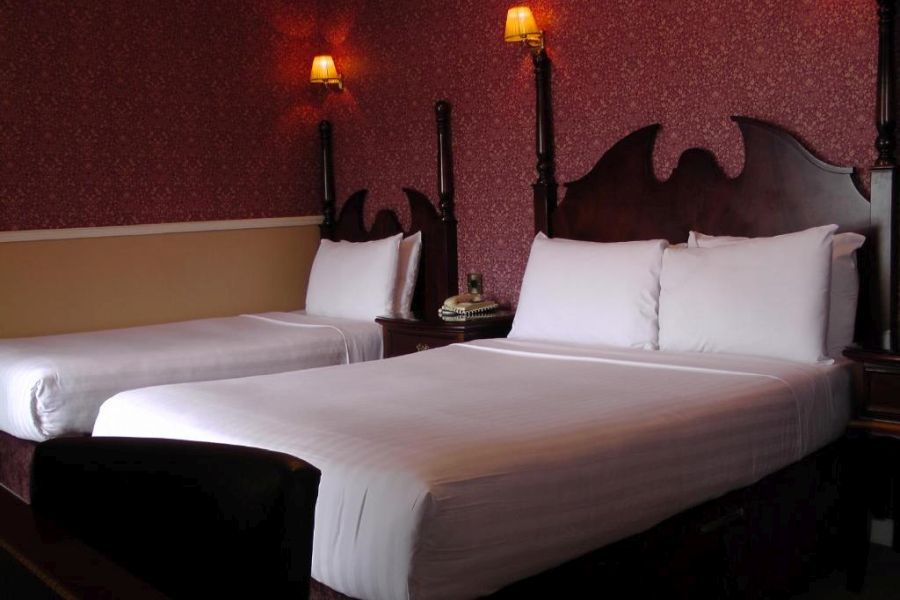Een driepersoonskamer met wit dekbedovertrek in een kamer met rood behang in het Atlantic Hotel Lahinch