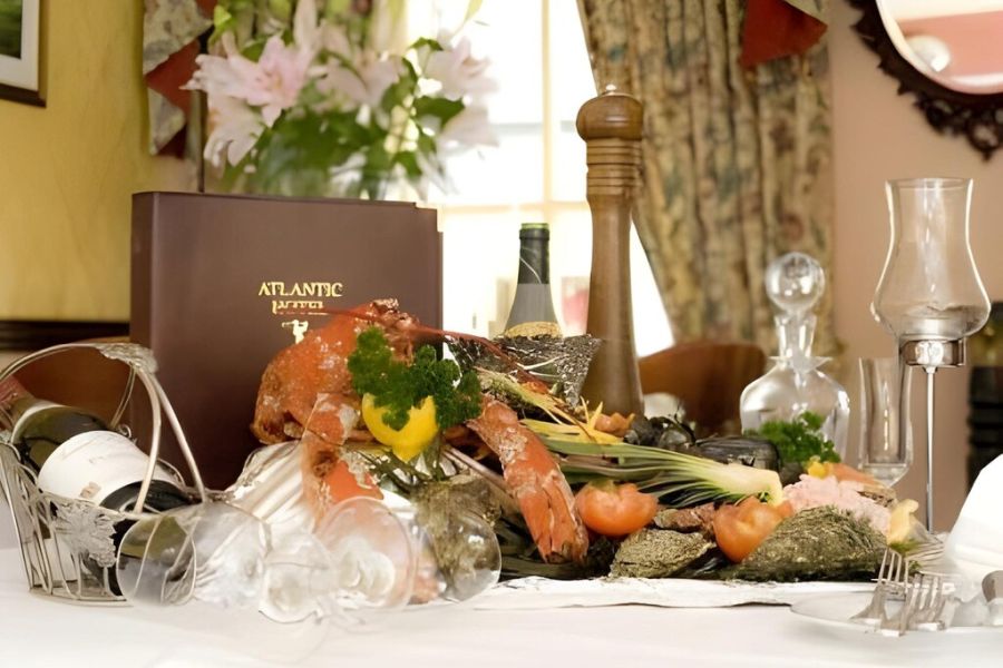 Een schaal met oesters, kreeft en groenten dat geserveerd wordt op een gedekte tafel