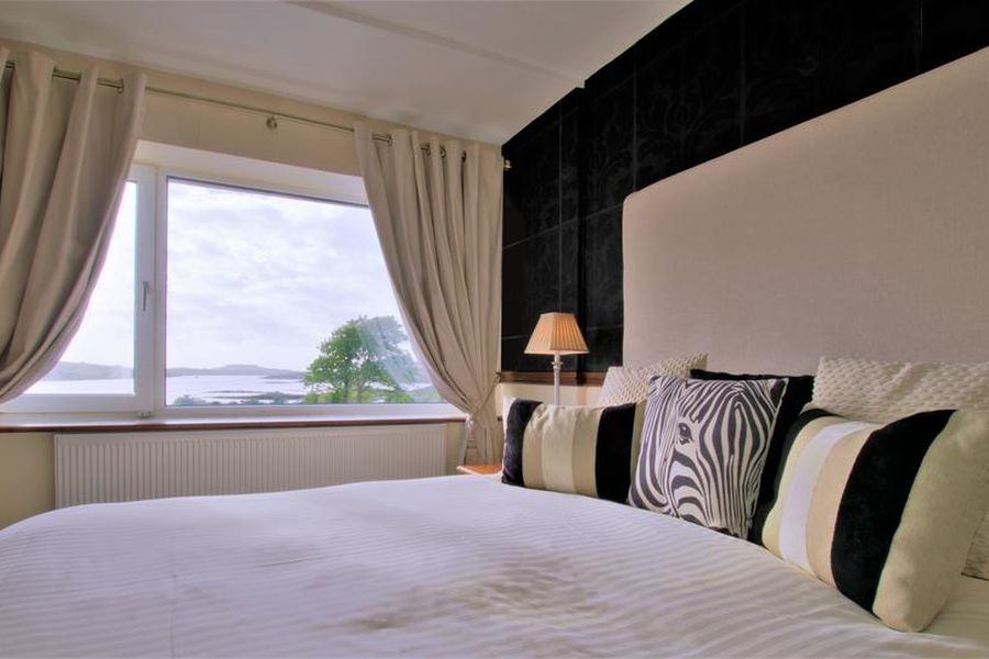 Een opgemaakt tweepersoonsbed in het Ardagh Hotel Clifden met uitzicht op het meer dat achter het hotel zit