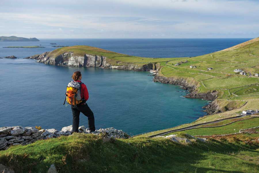 Hiker die uitkijkt over de baai van Dingle vanaf een heuvel