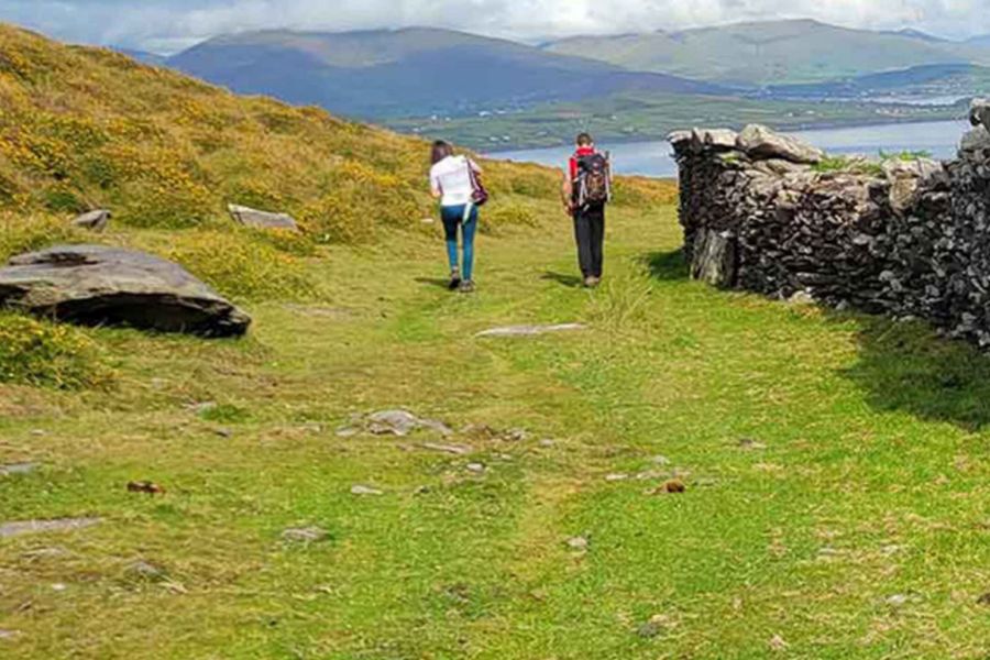 Twee hikers die over een heuvel richting de baai van Dingle hiken