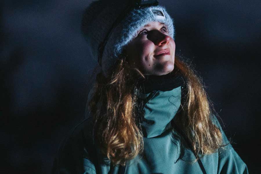 Vrouw kijkt naar de sterrenhemel tijdens een sneeuwschoenwandeling