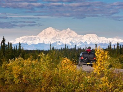 Een auto op de weg in Alaska met de bergen van Denali National Park op de achtergrond.