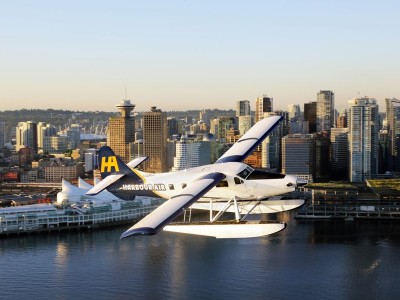 Watervliegtuig boven water met skyline van Vancouver op de achtergrond.